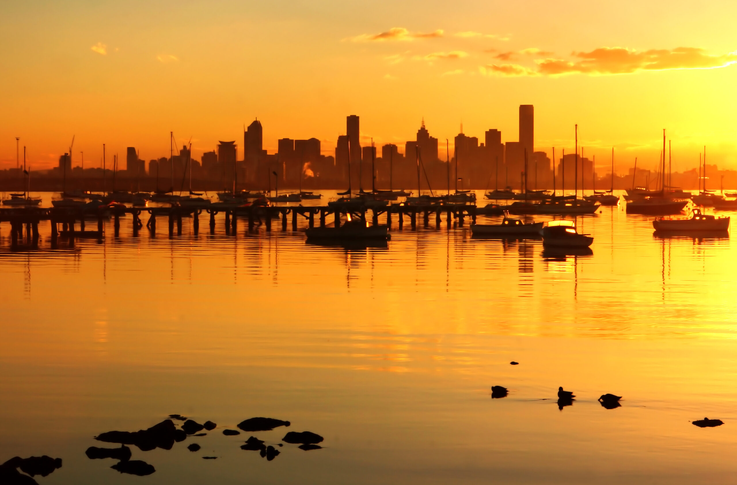 St Kilda Marina view across the port phillip bay to the Melbourne City CBD Skyline at dusk with all the sail boats and the smooth port phillip bay water with the Commercial and Residential Building of hte CBD in the background