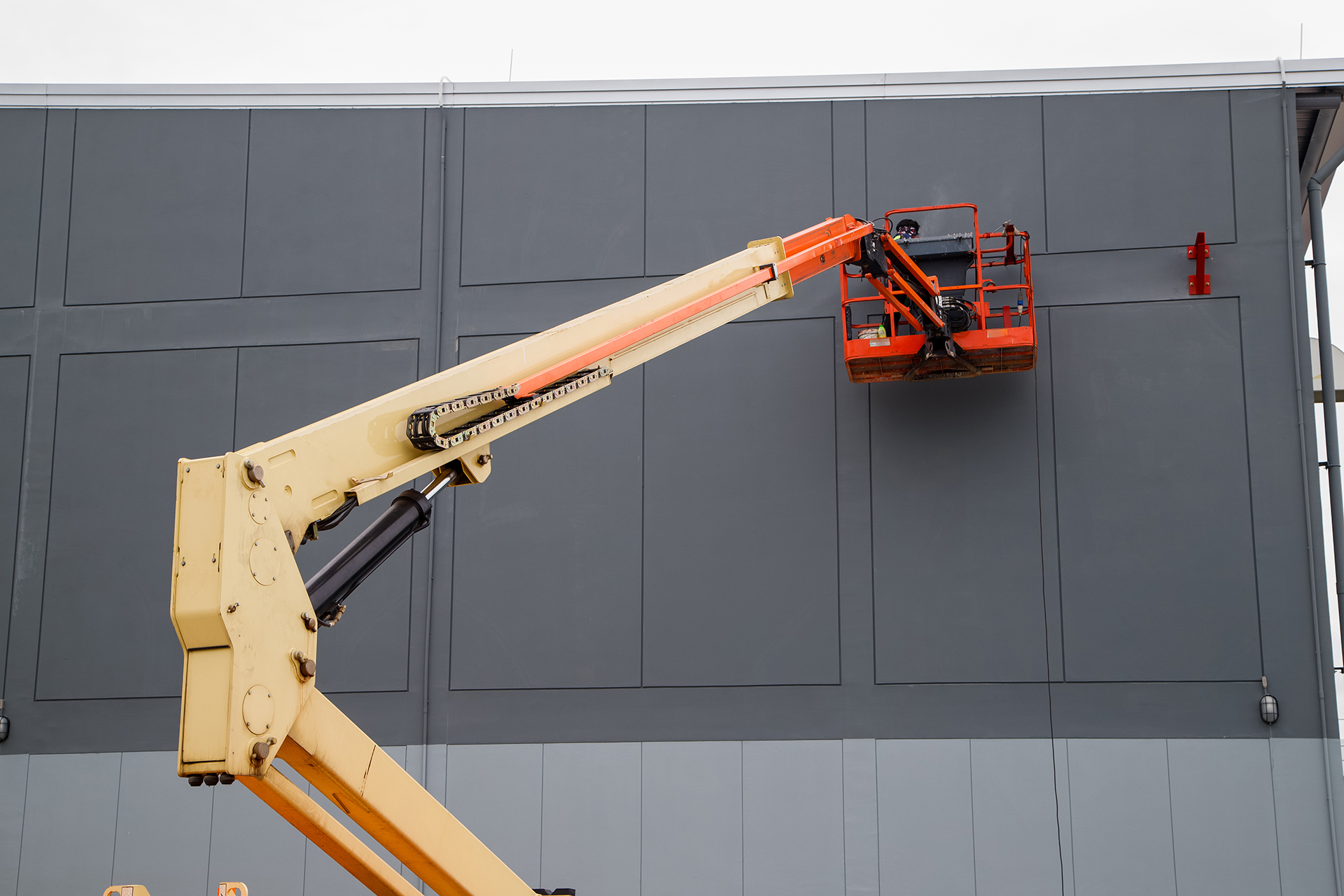 Property maintenance - Painting the exterior of a commercial retail property in dark grey on an EWP in a Sydney Suburb