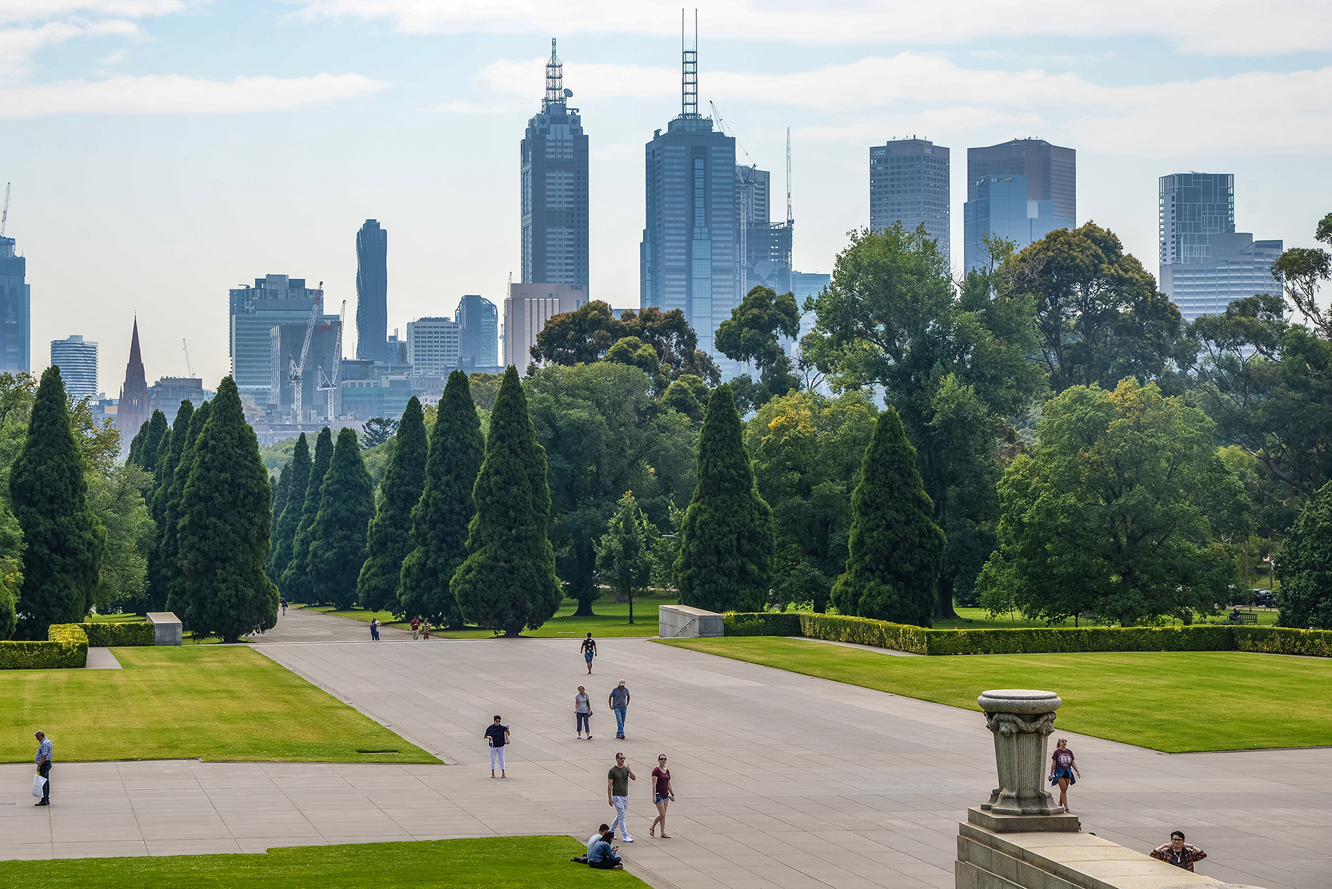 Melbourne CBD in view from the St Kilda Road Park with the SHRINE, People playing in the foreground and the City Buildings in the background, including 101 Collins Street and 333 Exhibition street