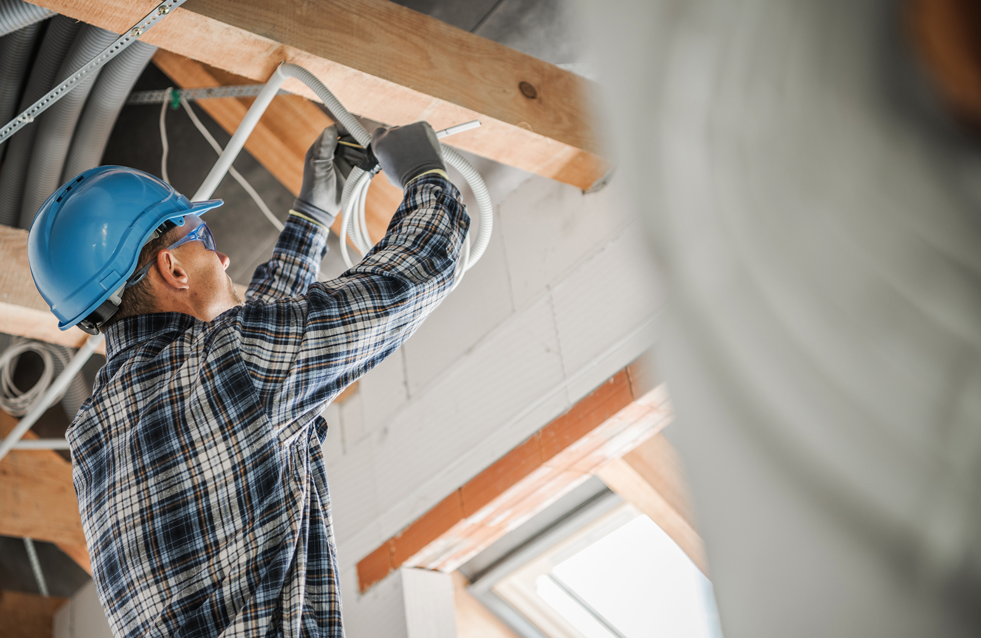 Performance Facility Management Field Employee performing electrical works onthe inside of a roof truss in Melbourne ina Strata residential property
