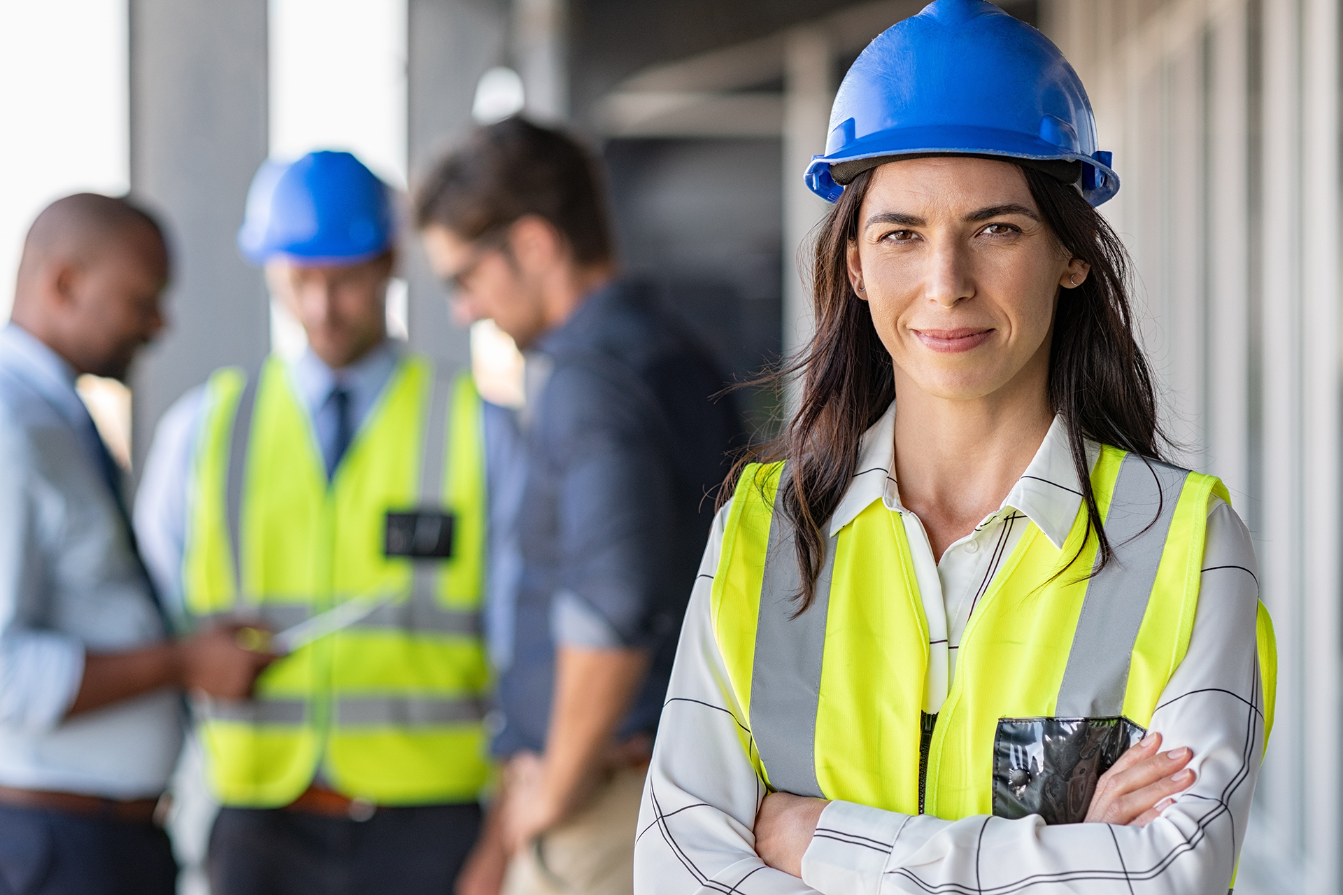 A professional contractor management meeting taking place on an active construction site, featuring executives dressed in business attire with hard hats and high-visibility safety vests discussing project coordination and operational planning. A female executive stands prominently at the front of the group, symbolising leadership, communication, and collaborative decision-making in commercial construction and facility management environments. The image represents contractor oversight, safety compliance, project management, stakeholder coordination, and building operations across commercial projects in Sydney, Melbourne, and Canberra.