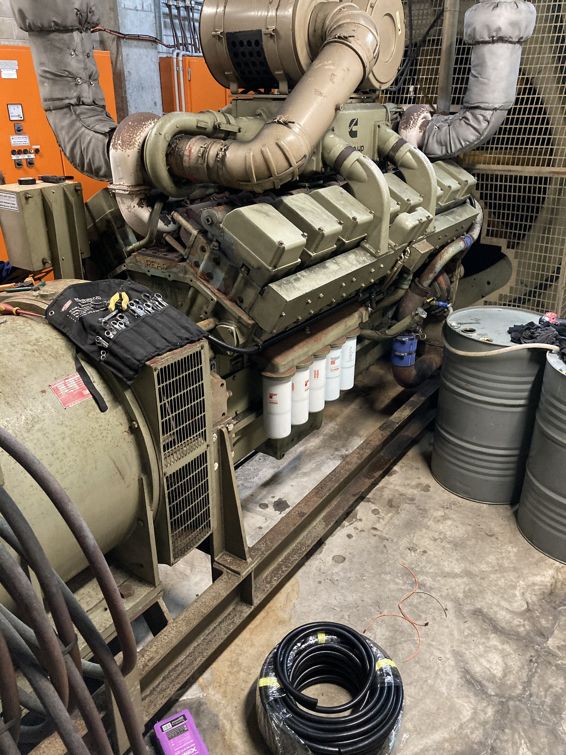 Technicians servicing an essential services diesel generator that provides emergency power to fire systems, HVAC and lifts during mains power failure.