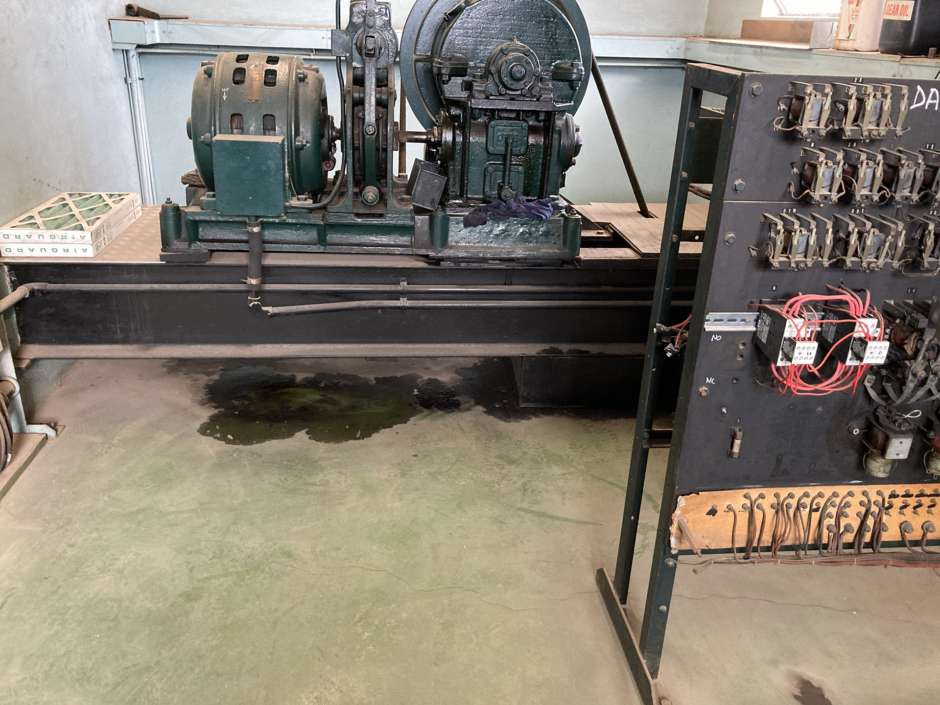 Old commercial lift motor and legacy lift switchboard inside a lift machine room requiring preventative maintenance and asset lifecycle assessment.