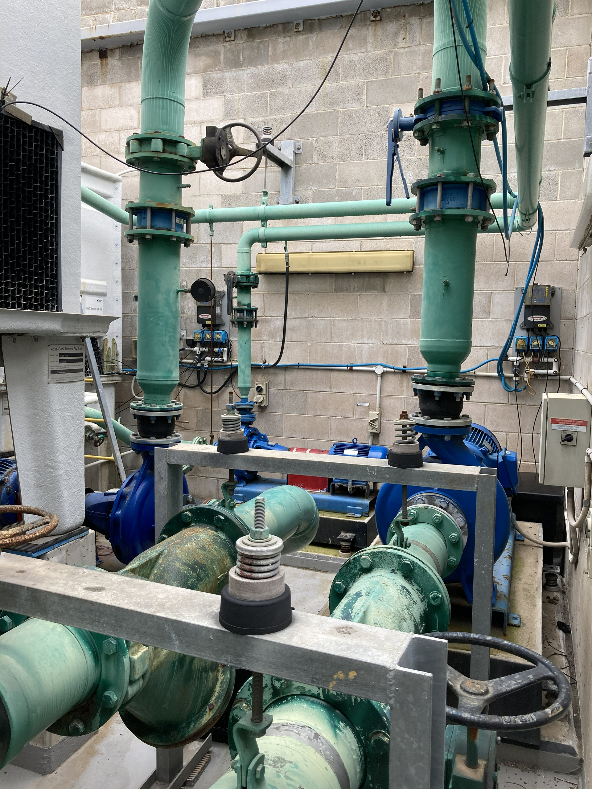 Commercial condenser water pumps and associated pipework serving a chilled water HVAC system in a commercial building plant room.
