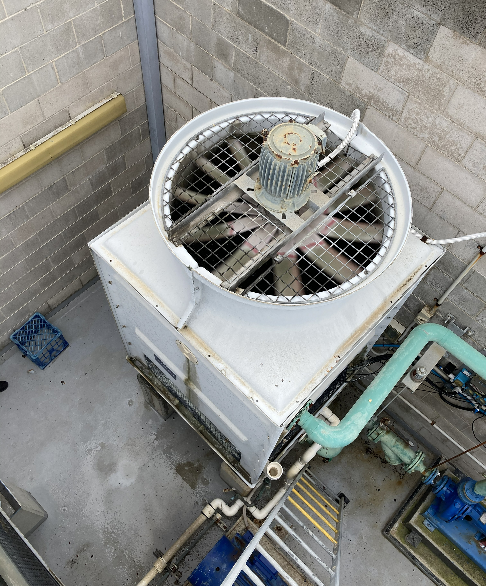 Commercial HVAC cooling tower on the rooftop plant area of a commercial building undergoing routine maintenance and inspection.